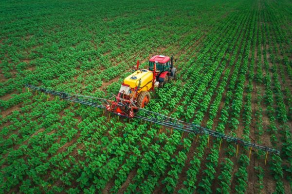 Farming tractor plowing and spraying on field